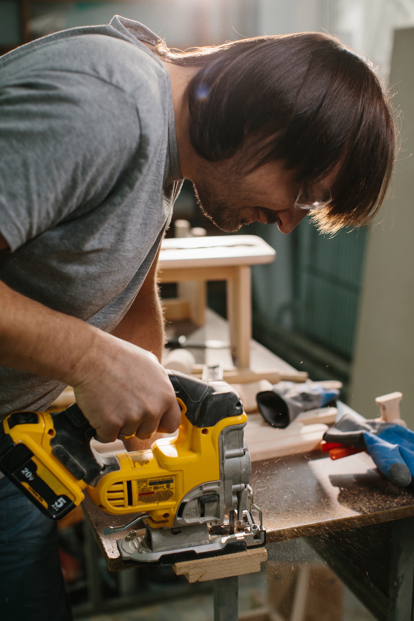 A wood-worker using a jigsaw to cut out a curve in a work piece of pine.